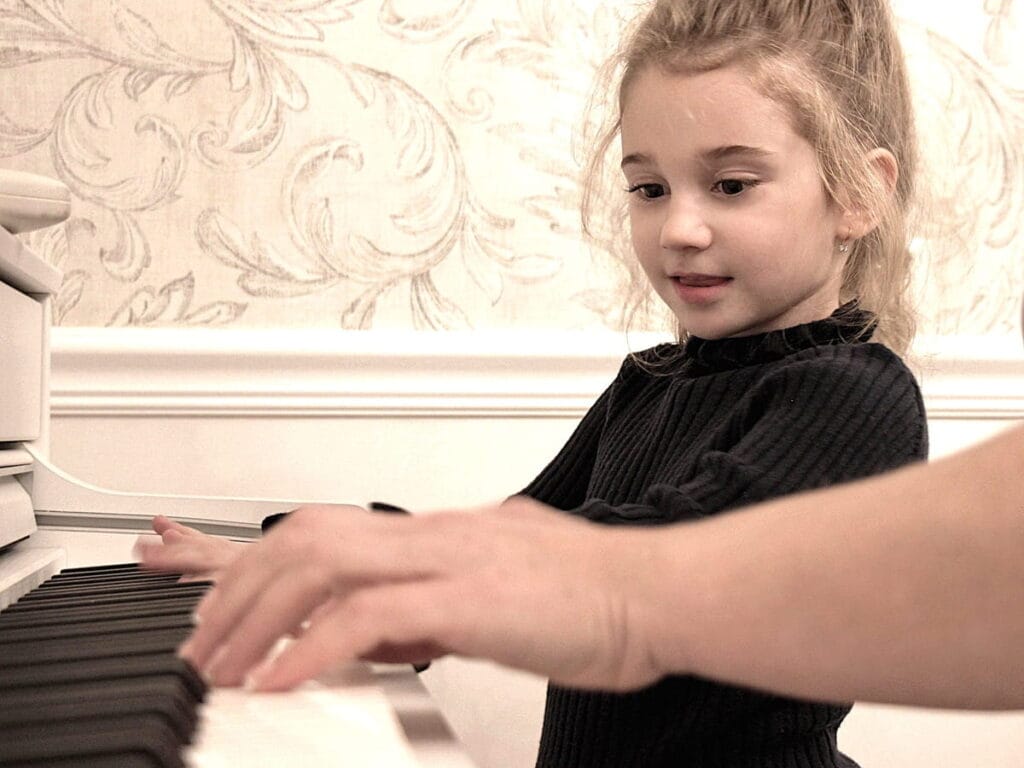 Enfant apprenant le piano à domicile avec l’aide d’un professeur