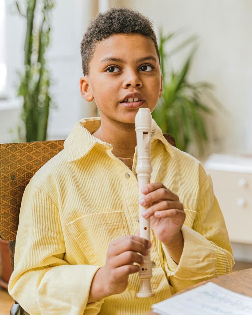 Enfant joue de la flûte à bec à domicile dans une pièce lumineuse