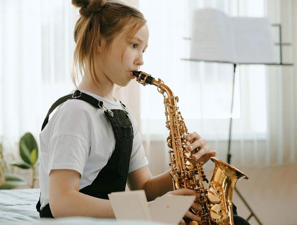 Jeune adolescente joue du saxophone à domicile dans une pièce lumineuse