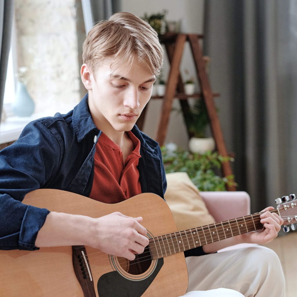 Adulte pratiquant la guitare à domicile dans son salon.