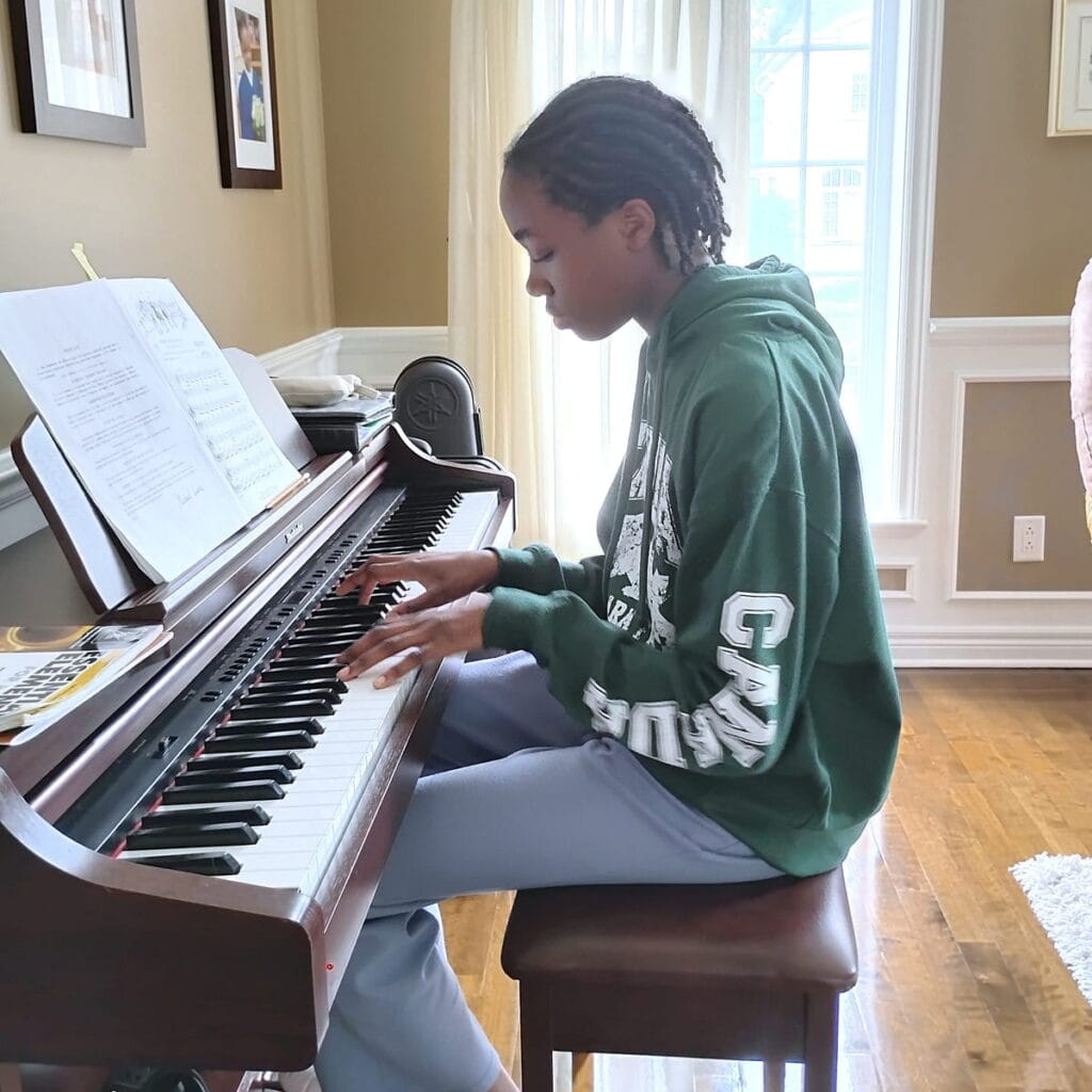 Adolescente pratiquant le piano à domicile lors d'un cours adapté à son niveau.