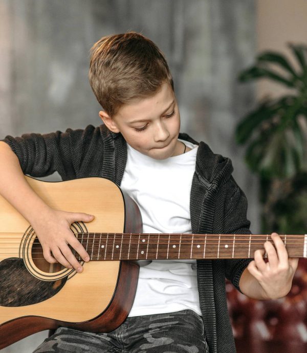 Adolescent qui pratique la guitare chez lui lors d’un apprentissage à domicile